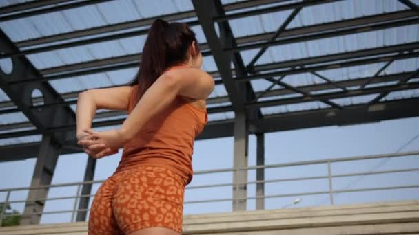 Jonge, aantrekkelijke vrouw doet een aantal schouder strekt voorafgaand aan outdoor workout. — Stockvideo