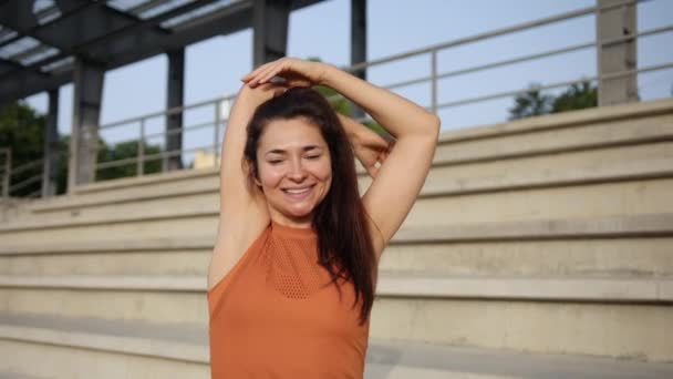 Jonge, aantrekkelijke vrouw doet een aantal schouder strekt voorafgaand aan outdoor workout. — Stockvideo