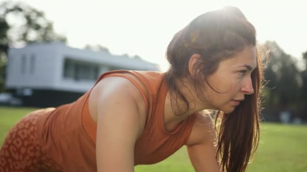 フィットネス初心者のための運動。公園で膝の腕立て伏せをしている若い女性. — ストック動画