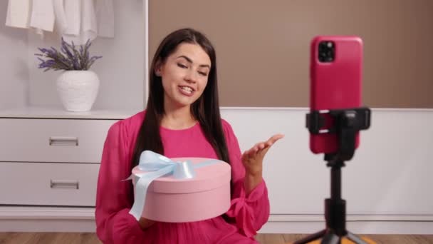 Joven, hermosa blogger chica escribe un video para blog en el que ella desempaca regalo — Vídeo de stock