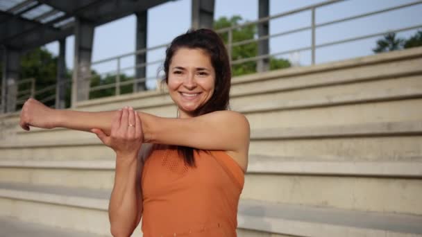 Женщина, которая растягивается на улице. Молодая кавказская атлетка делает разминку — стоковое видео