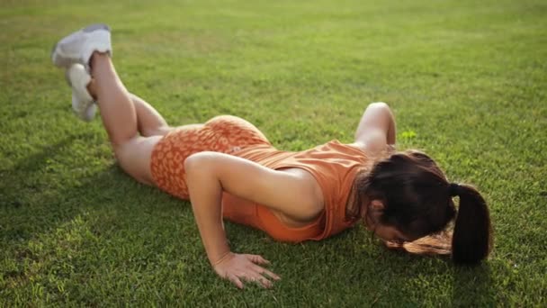 Kaukasisch model. Een blanke vrouw die push-ups doet in het park. Jong meisje — Stockvideo