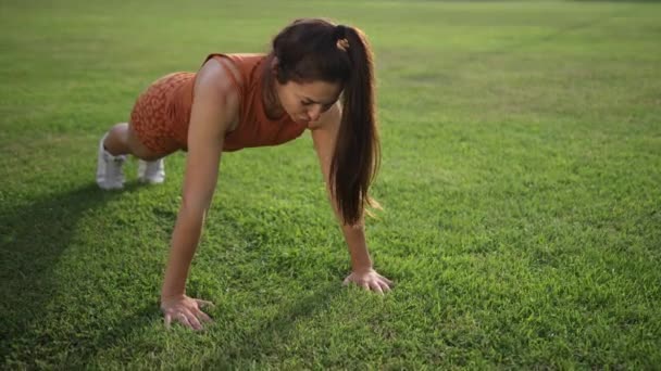 Sexy Frau auf dem grünen Gras liegend. Fitness-Fußbodentraining bewegt die Hände. — Stockvideo