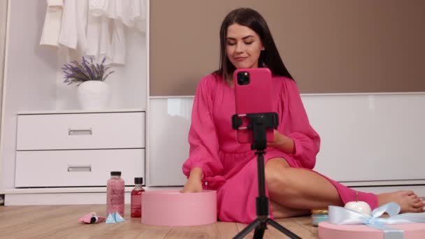 Jonge vrouwelijke influencer uitpakken van grote kartonnen doos, zitten mobiele telefoon — Stockvideo