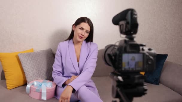 Smiling pretty young woman influencer unpacking big cardboard box, in sofa — Stock Video