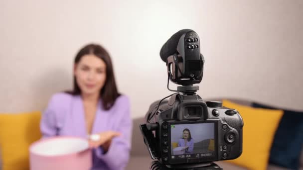 Souriant jolie jeune femme influenceur déballage grande boîte en carton, dans le canapé — Video