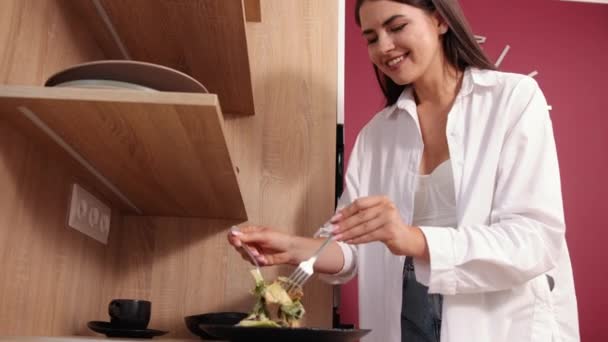 Mujer joven de pie en la cocina moderna preparando ensalada, feliz cocina milenaria — Vídeos de Stock