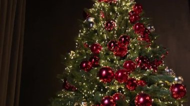 Noel ağacı, zarif bir dekor, rahat bir atmosfer. Güzel dekore edilmiş Noel ağacı kırmızı ve gümüş takılar, sıcak beyaz ip ışıkları, ve koyu yeşil dallar.