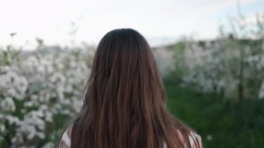 Arkaya bakıyorum, çiçek açan manzara, gülümsüyorum. Çiçek açan ağaçlarla yeşil bahçede koşan kadın gülümsüyor ve arkasına bakıyor..