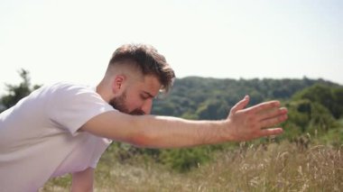 Genç adam, açık hava yogası, yoga enerjisi. Siyah şort ve beyaz tişört giyen genç adam, mor çimen tarlasında dengeli yoga pozu veriyor..