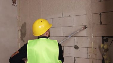 Püskürtme macunu, yüzey kaplaması, bina yenileme. İşçi spreyinin duvarlara çimento sıktığı gibi sert şapka ve yüksek çözünürlüklü yelek..