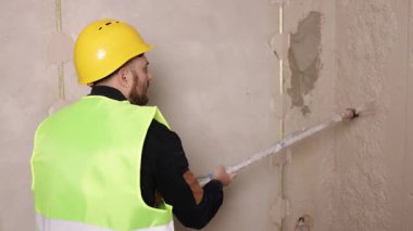 Çimento harcı, kalifiye işçilik, inşaat aletleri. İşçi etkin yenileme alanında sprey tabancayla beton bazlı alçıyı blok çalışmasına uygular.