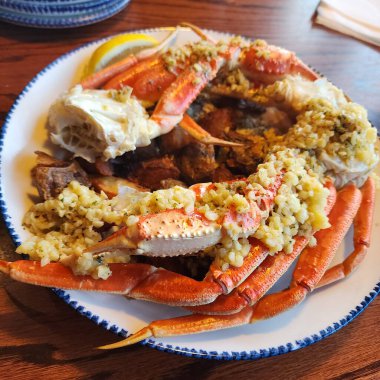 Kanada 'da bir restoranda servis edilen tabakta sarımsaklı tereyağlı pişirilmiş yengeç bacağı, deniz ürünleri mutfağı, sıcak aydınlatma ve iştah açıcı sunum..