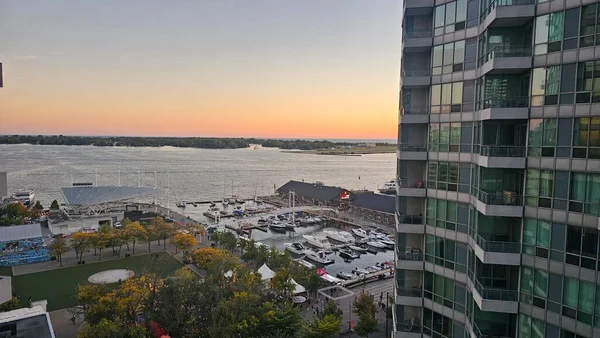 Toronto Limanı 'nda gün batımı manzarası yükseldi. Tekneler, rıhtım parkı ve Toronto, Kanada şehir merkezinde sıcak bir akşam gökyüzü altında modern yerleşim binaları..