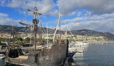 Kopya Christopher Columbus gemisi Santa Maria Funchal marinasında demirlemiş şehrin silueti ve arka planında dağlar, Madeira, Portekiz. 6 Eylül 2024