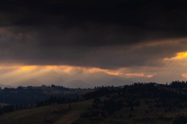 Yuvarlanan dağ tepelerinin kasvetli sonbahar manzarası ve altın günbatımı ışınlarıyla aydınlanan karanlık bulutlar Litwinka 'nın Czarna Gora' daki manzarası, Polonya dağları