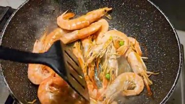 Lezzetli bir İspanyol paella yemeğinin parçası olmaya hazır, tavada cızırdayan lezzetli karideslerin yakın çekimi.