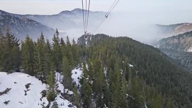 Dağ sırtı üzerinde kablo araba manzarası, aşağısı sisli vadi, kış seyahati ve turizm konsepti dramatik yükseklik ve atmosfer perspektifini gösteriyor.