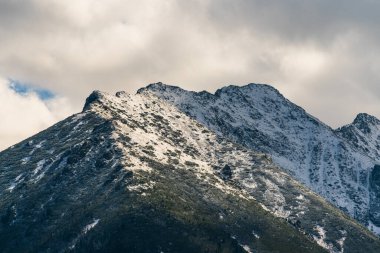 Polonya 'nın Rusinowa Polana kentinin görkemli dağ manzarası kayalık yamaçlarda karlar ve aşağıda yemyeşil bitkiler var.