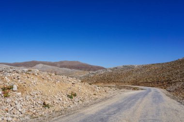 Türkiye 'de güneşten ıslanmış, ıssız bir dağ geçidi seyrek bitki örtüsü ve engebeli arazi uzak tepelere doğru gidiyor.