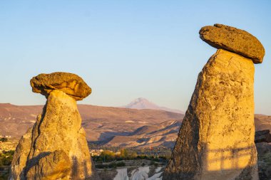 Peri bacaları olarak bilinen ikonik kaya oluşumları, Türkiye 'nin Kapadokya şehrinin eşsiz manzarasında, batan güneşin sıcacık parıltısıyla yıkanıyor.