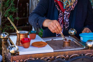 Bir kişi sıcak kumda ısıtılan bakır bir kafenin zeminini karıştırarak Türk kahvesini dikkatlice hazırlıyor