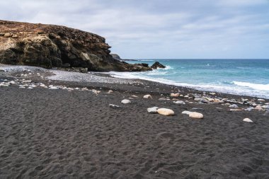 Ajuy 'un engebeli kıyı şeridinde parlak mavi Atlantik' le buluşan volkanik kayalıklarla çevrili ve pürüzsüz taşlarla kaplı çarpıcı siyah bir kumsal bulunur.