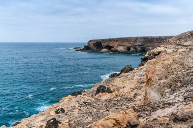 Dramatik volkanik kayalıklar ve deniz mağaraları Atlantik Okyanusu 'nun canlı mavi bir zemin sağladığı Ajuy, Fuerteventura kıyıları boyunca uzanır.