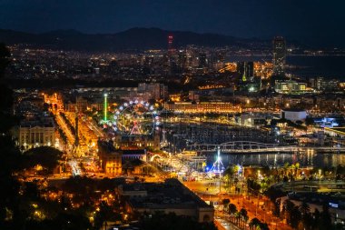 Gece hareketli liman ve şehir siluetinin panoramik görüntüsü aydınlatılmış eğlence merkezleri ve marina etkinlikleri sergileniyor.