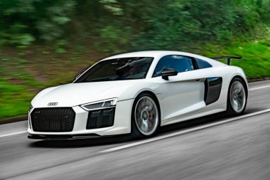 Otoyolda beyaz bir Audi R8 'in yuvarlanan çekimi, lüks süper araba hareket halinde.