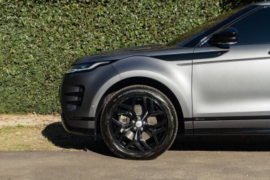 Gri Range Rover Evoque alaşımlı tekerlek yakın çekim, lüks SUV ön uç detay, yeşil doğa arka plan
