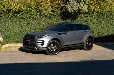 Gri Range Rover Evoque ön manzara üç çeyrek, lüks SUV yeşil çimenlerin önüne park edilmiş.