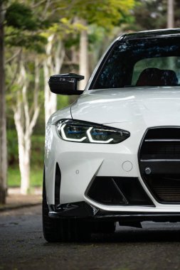 Beyaz BMW M3 müsabaka lazer far yakın çekim, spor sedan ön koruma park ayarında mavi aksanlı