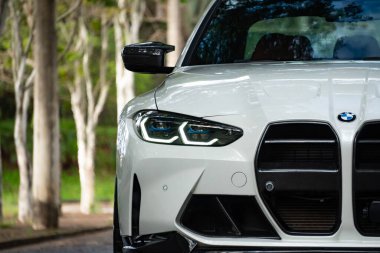 Beyaz BMW M3 müsabaka lazer far yakın çekim, spor sedan ön koruma park ayarında mavi aksanlı