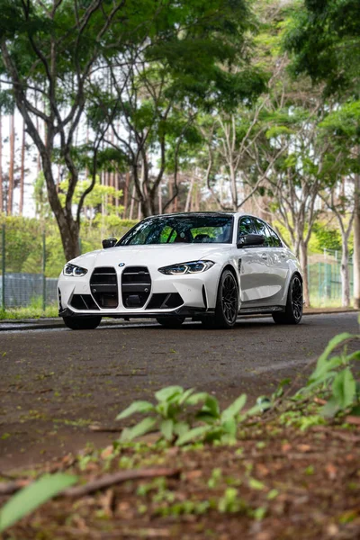 Beyaz BMW M3 müsabakası ön manzara üç çeyrek, spor sedan açısı yolda alçak bitki örtüsü