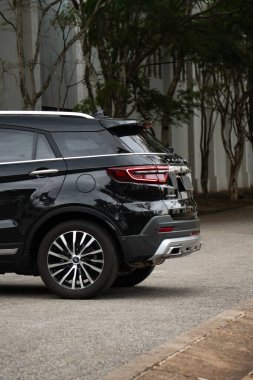 Siyah bir Ford Bölgesi Titanyumu 'nun arka çeyreği, ağaçlık yolda son model bir SUV dış çekim.