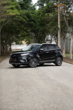 Siyah Ford arazi aracı, ağaçlık bir yolda park edilmiş, lüks, yoğun, harici bir atış.