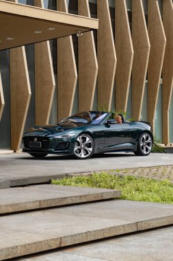 Yeşil Jaguar F tipi ön manzara üç çeyrek manzara, üstü açık lüks araba çağdaş mimari tarafından tepeden tırnağa park edilmiş.
