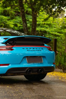 Mavi Porsche 911 Targa 4 GTS arka kapak, konforlu spor araba yolu manzaralı.