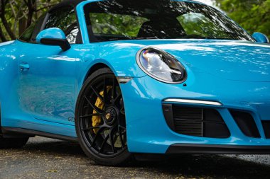 Mavi Porsche 911 Targa 4 GTS ön teker ve far yakın çekim, orman yolunda park edilmiş performans arabası