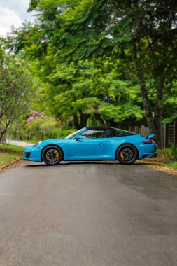 Mavi Porsche 911 Targa 4 GTS yan profili, çatısı orman yolunda kapalı lüks spor araba