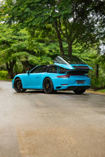 Mavi Porsche 911 Targa 4 GTS arka açısı yarı açık üstü, lüks spor arabası özel bahçede.