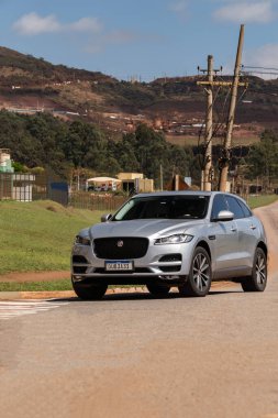 Gümüş Jaguar F-Pace önde. Kırsal yolda birinci sınıf lüks SUV.