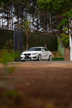 Beyaz BMW M235i ön manzara alçak açı, lüks spor coupe yolda orman ile çevrili