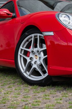 Kırmızı Porsche Cayman S tekerleği ve fren detayı, lüks spor araba ön tarafı yakın plan.