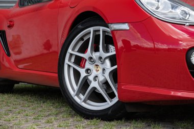Kırmızı Porsche Cayman S tekerleği ve fren detayı, lüks spor araba ön tarafı yakın plan.