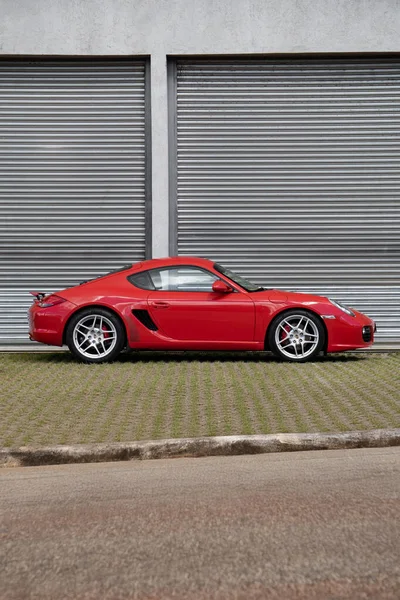 Kırmızı Porsche Cayman 'ın yan görünüşü, lüks spor arabaları endüstriyel garajın oraya park edilmiş.