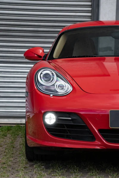 Kırmızı Porsche Cayman 's ön far ışığı odaklı çekim, metal kapının önünde lüks spor coupe