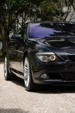 Siyah BMW 650i ön taraf görünümü, lüks Coupe far ışığı yeşil ağaçlar arka plan odaklı çekim