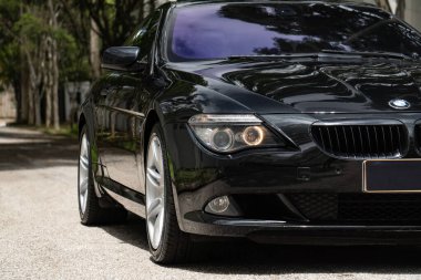 Siyah BMW 650i ön taraf görünümü, lüks Coupe far ışığı yeşil ağaçlar arka plan odaklı çekim